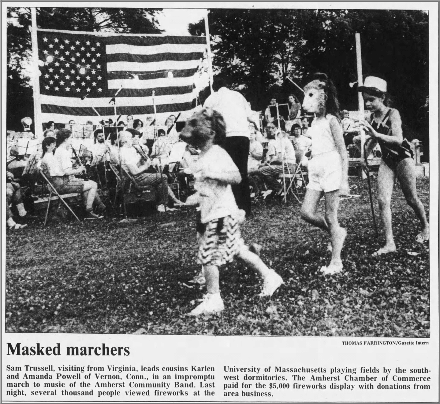 Daily Hampshire Gazette feature from July 5, 1990 about the Amherst Community Band playing during fireworks. Caption reads: Masked marches: Sam Trussell, visiting from Virginia, leads cousins Karlen and Amanda Powell of Veron, Conn., in an impromptu march to the music of the Amherst Community Band. Last night, several thousand people viewed fireworks at the University of Massachusetts playing fields by the south-west dormitories. The Amherst Chamber of Commerce paid for the $5,000 fireworks display with donations from area business.